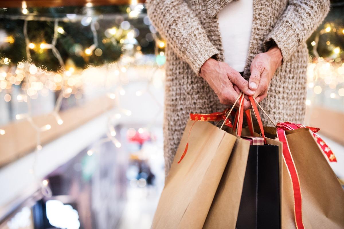 older woman holding three shopping bags while doing some black friday shopping