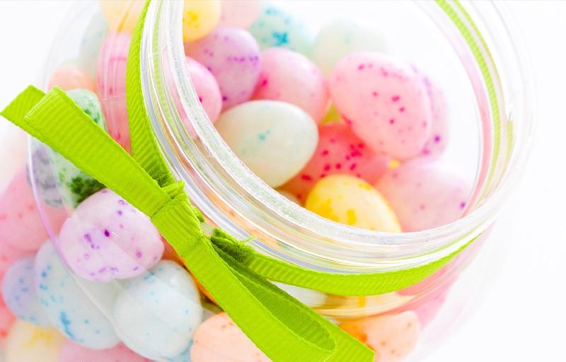 Close-up of a jar tied with a green ribbon, filled with colorful speckled eggs.