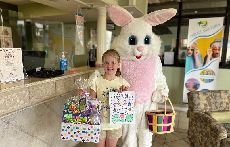 A child with Easter gifts standing next to a person in a bunny costume.