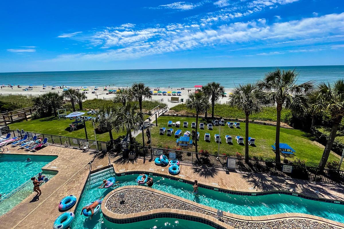 Outdoor lazy river and swimming pool plus a green lawn with resort style seating and ocean views