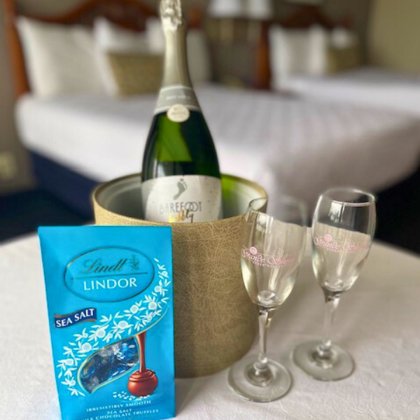 a bottle of champagne on ice with champagne flutes and a box of chocolates