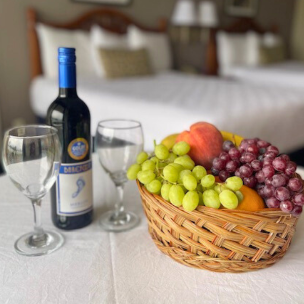 a bottle of wine and a fruit basket with grapes and bananas