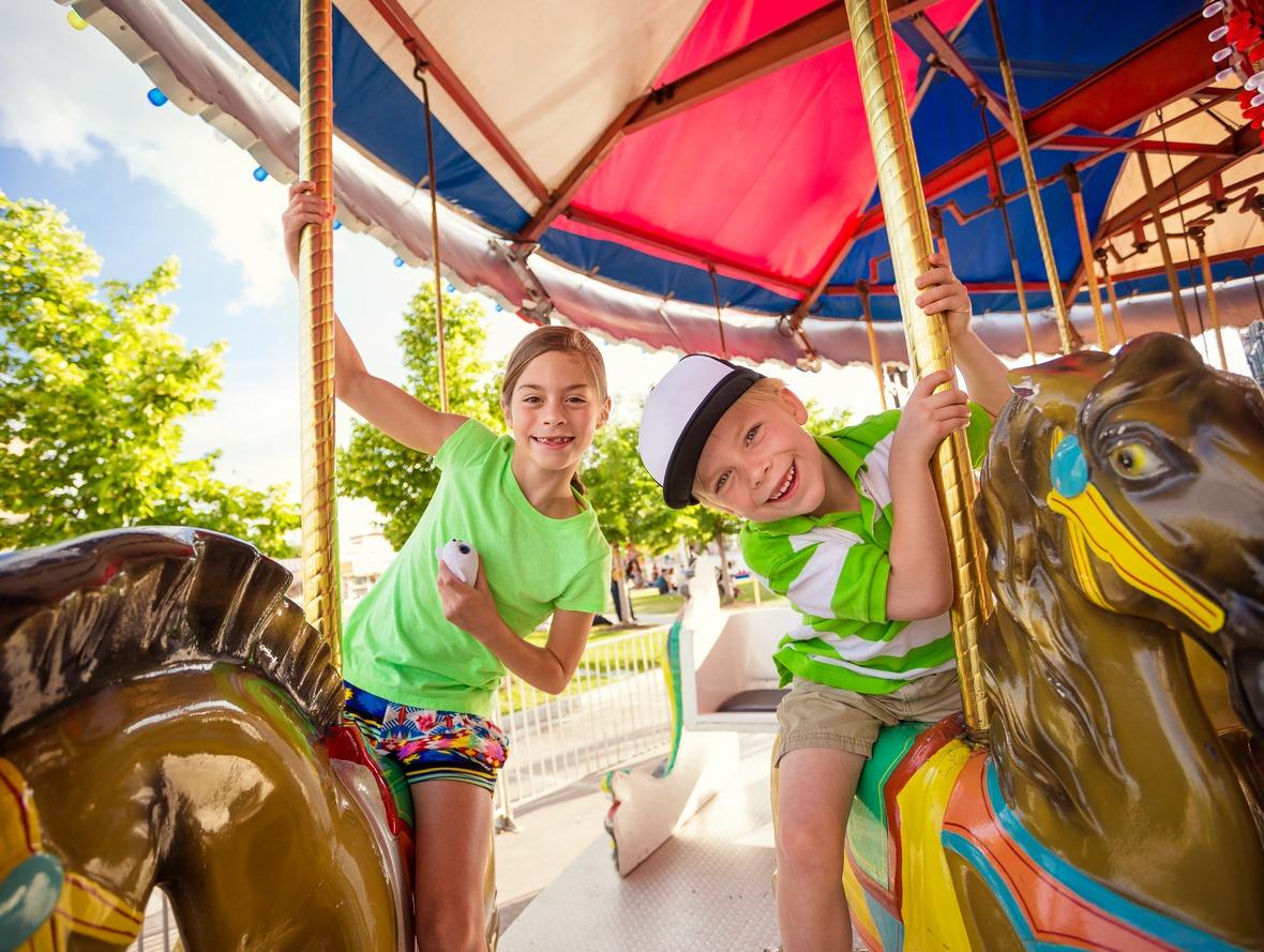 Two cute kids enjoying a ride on a fun carousel at Broadway at the Beach. 