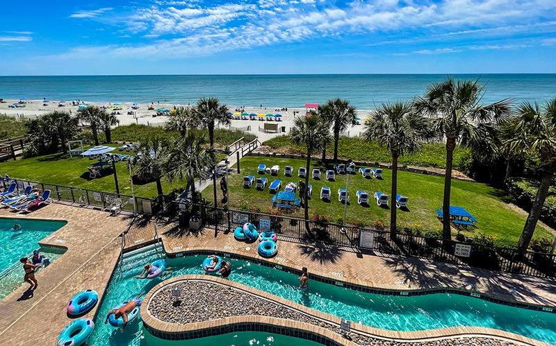 View of an outdoor pool and lazy river at Grande Shores with the ocean in the background