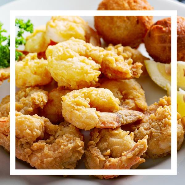 Plate of fried shrimp with hushpuppies and a lemon wedge