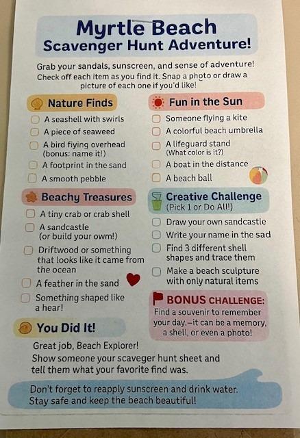 Smiling worker cleaning with a spray bottle in a commercial kitchen.